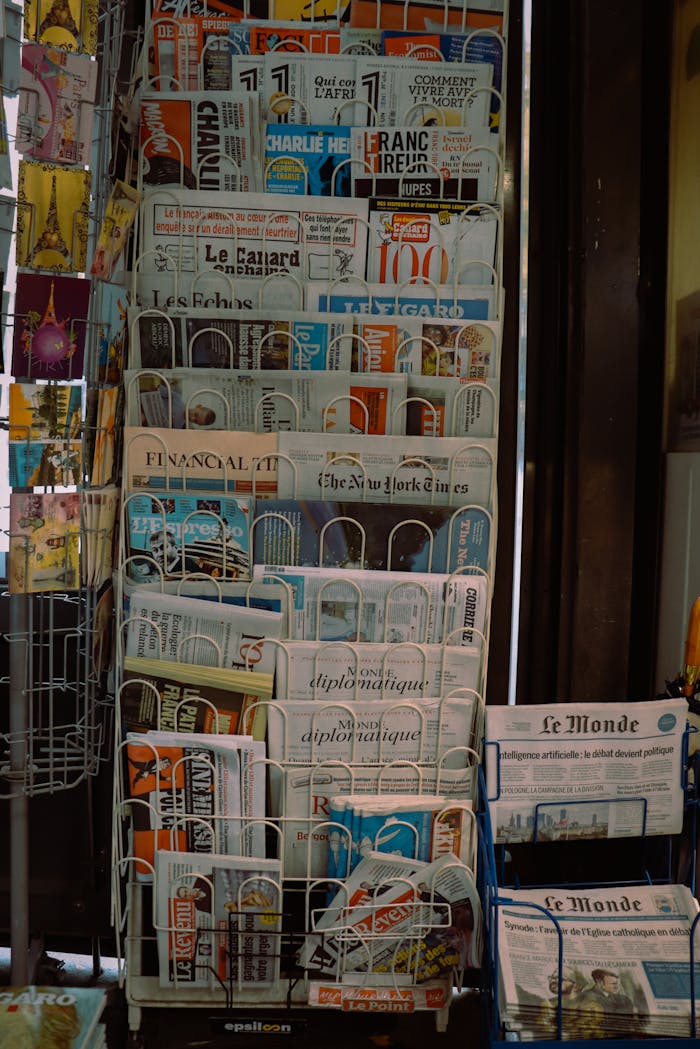 contact-header A Paris newsstand displaying international newspapers, reflecting diverse media in a French setting.