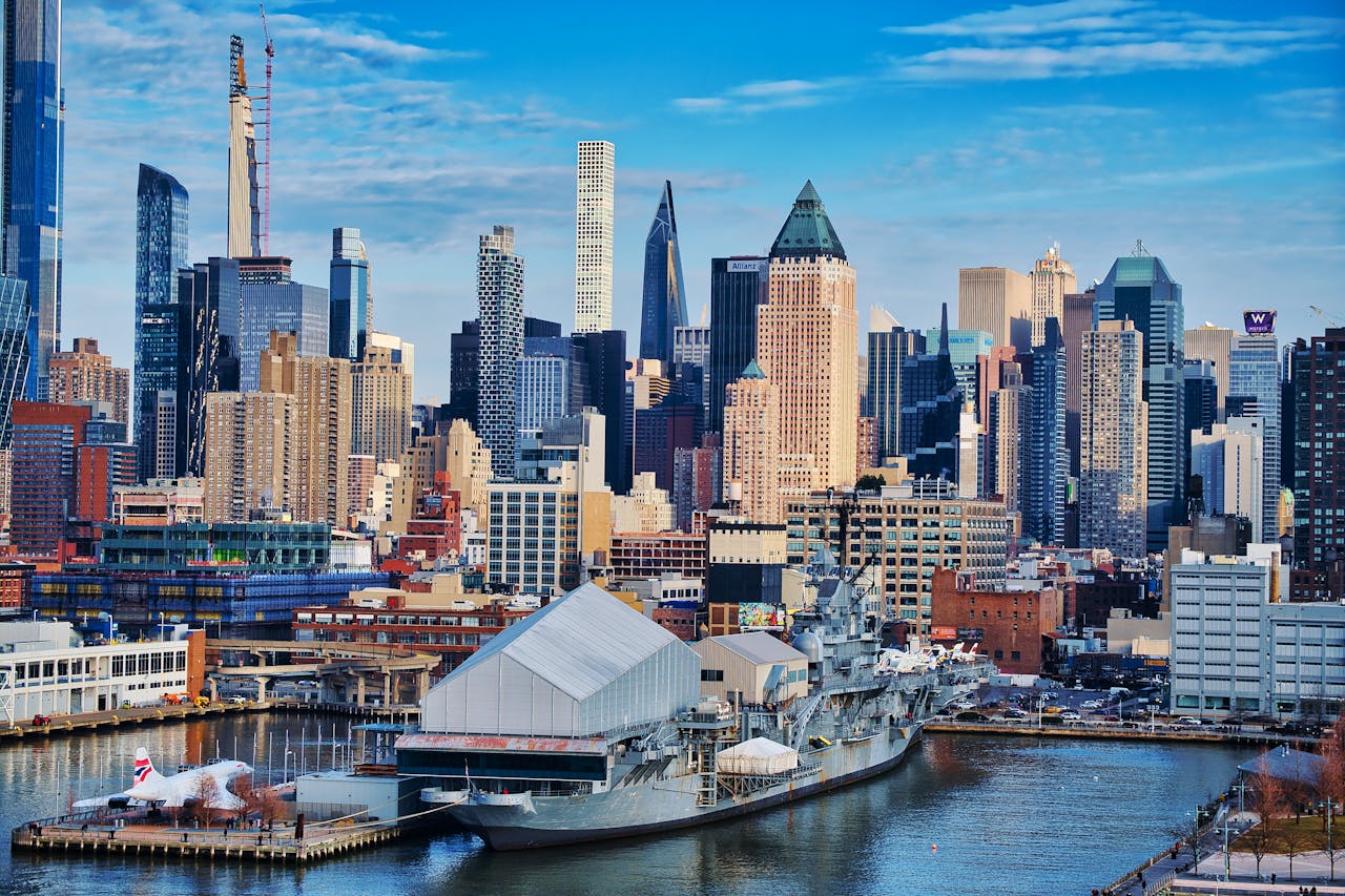 Vibrant view of New York City's skyline with waterfront and iconic skyscrapers under a bright sky.